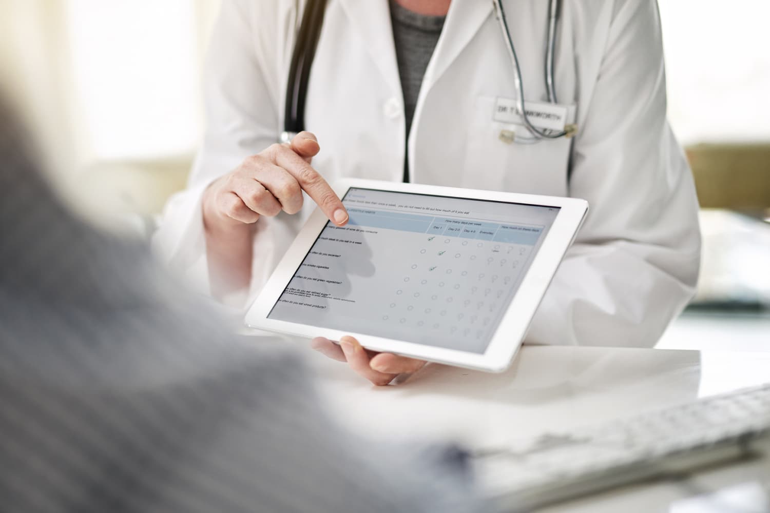 Doctor asking patient to leave a review for their medical practice on a tablet