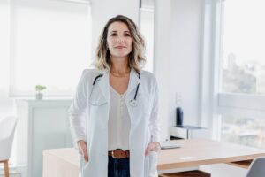 Young blonde doctor dressed casually with white coat and stethoscope