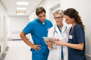 Mature female doctor discussing medical report with nurses in hospital hallway