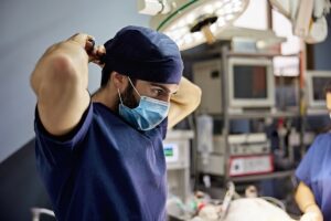 Medical provider securing mask and medical gear before getting to work on a patient