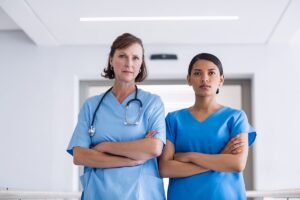 Two serious physicians in medical gear with their arms crossed