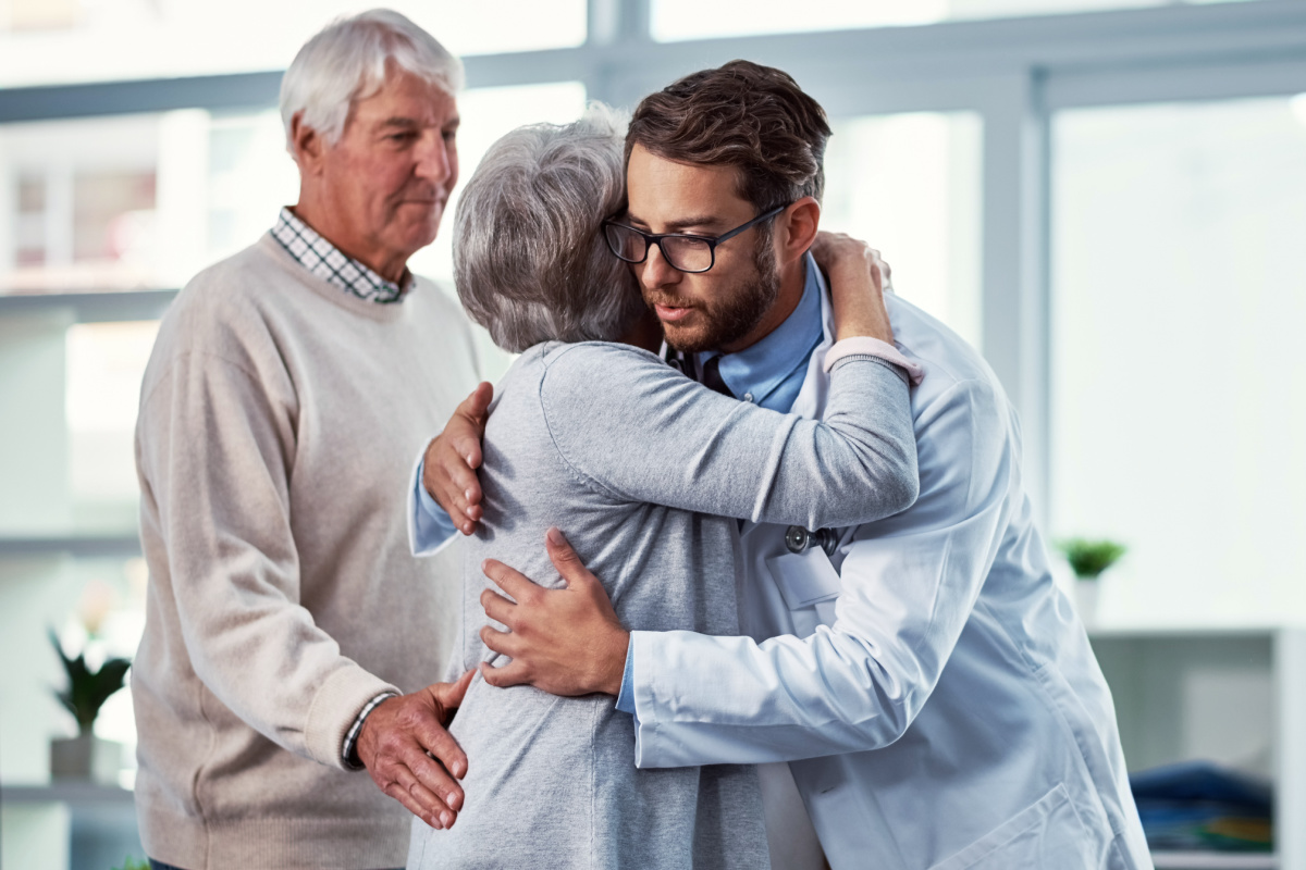 Male physician hugging elderly female patient