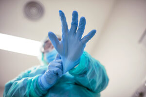 Faceless male physician putting on medical gloves