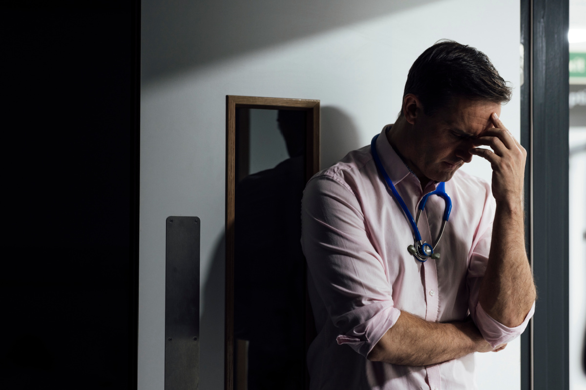 Frowning male physician in a dark room after filing for bankruptcy