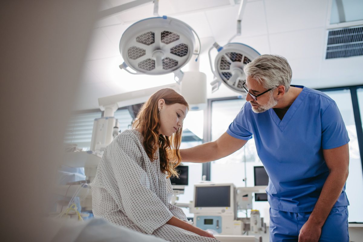 Male surgeon talking to teenage girl in operating room