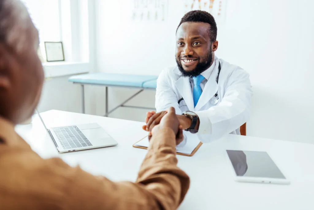 Male doctor shaking female patient's hand