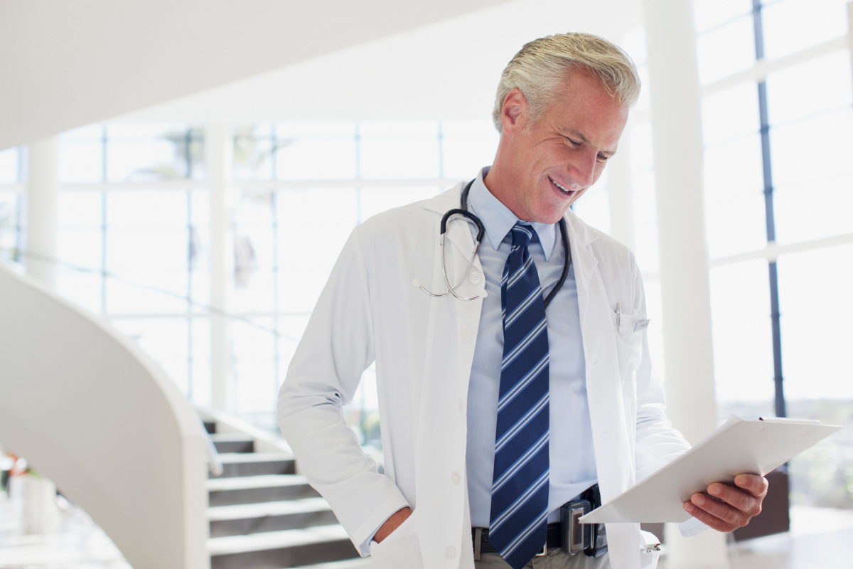 Mature male physician signing off on aesthetic practice paperwork as medical director