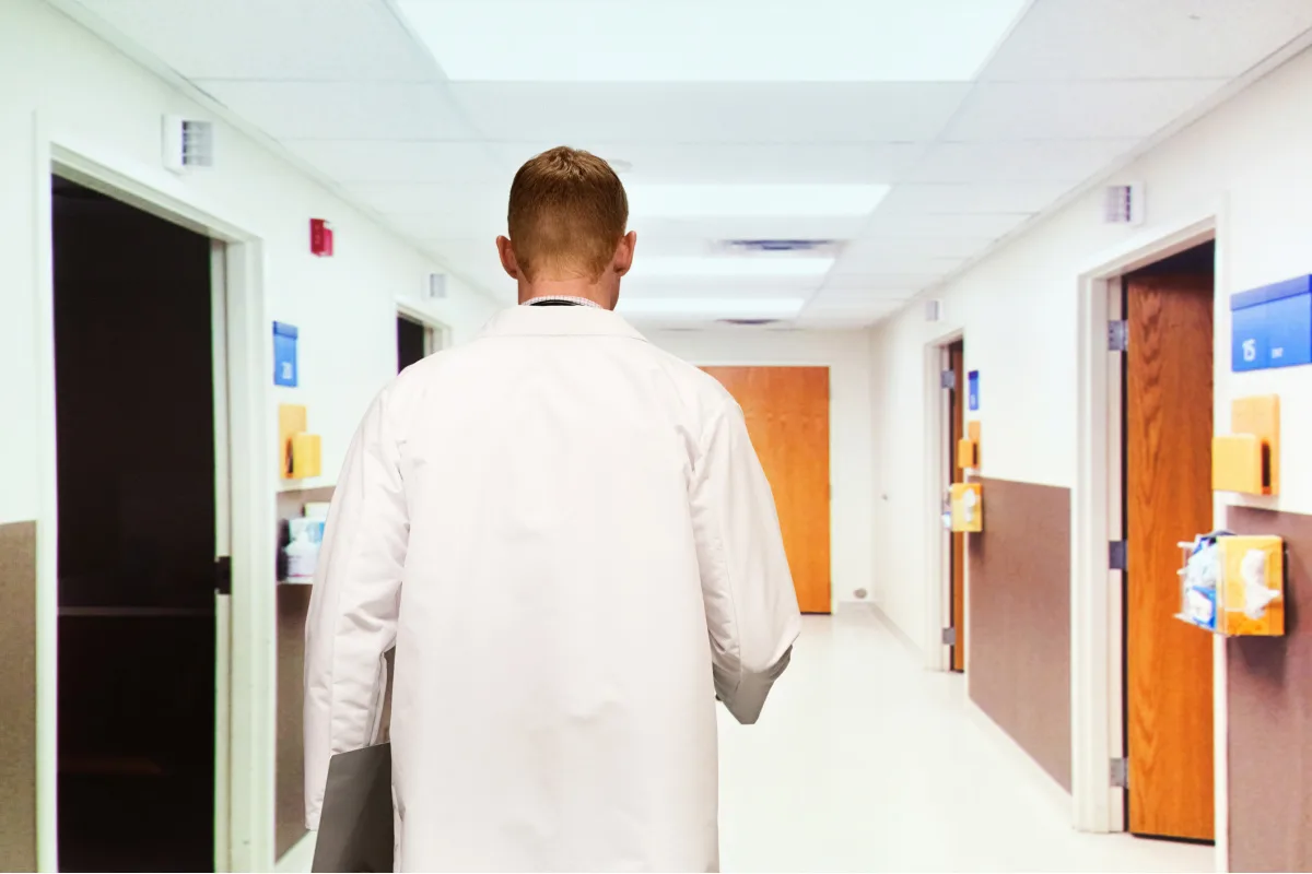 Male physician walking through empty hallway