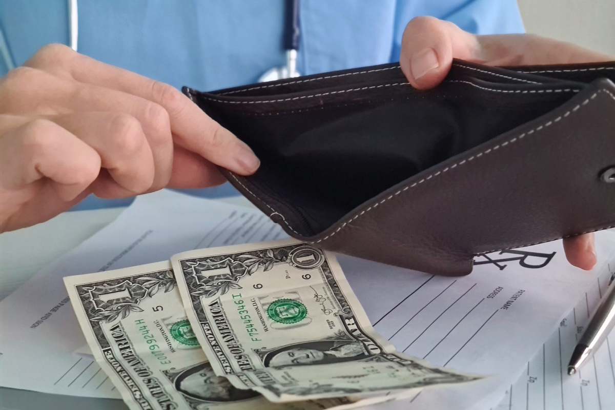 Bankrupt doctor taking dollar bills out of empty wallet