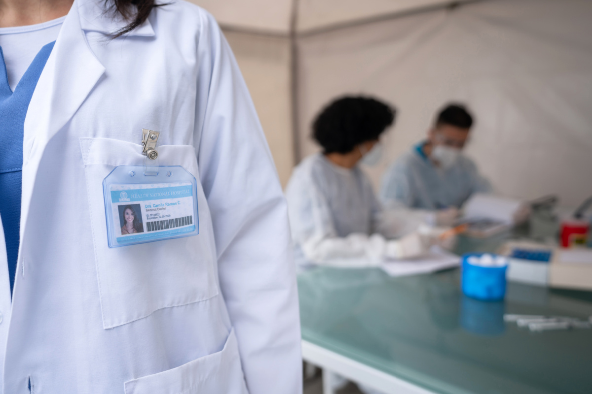Faceless female physician in a tent with other healthcare workers