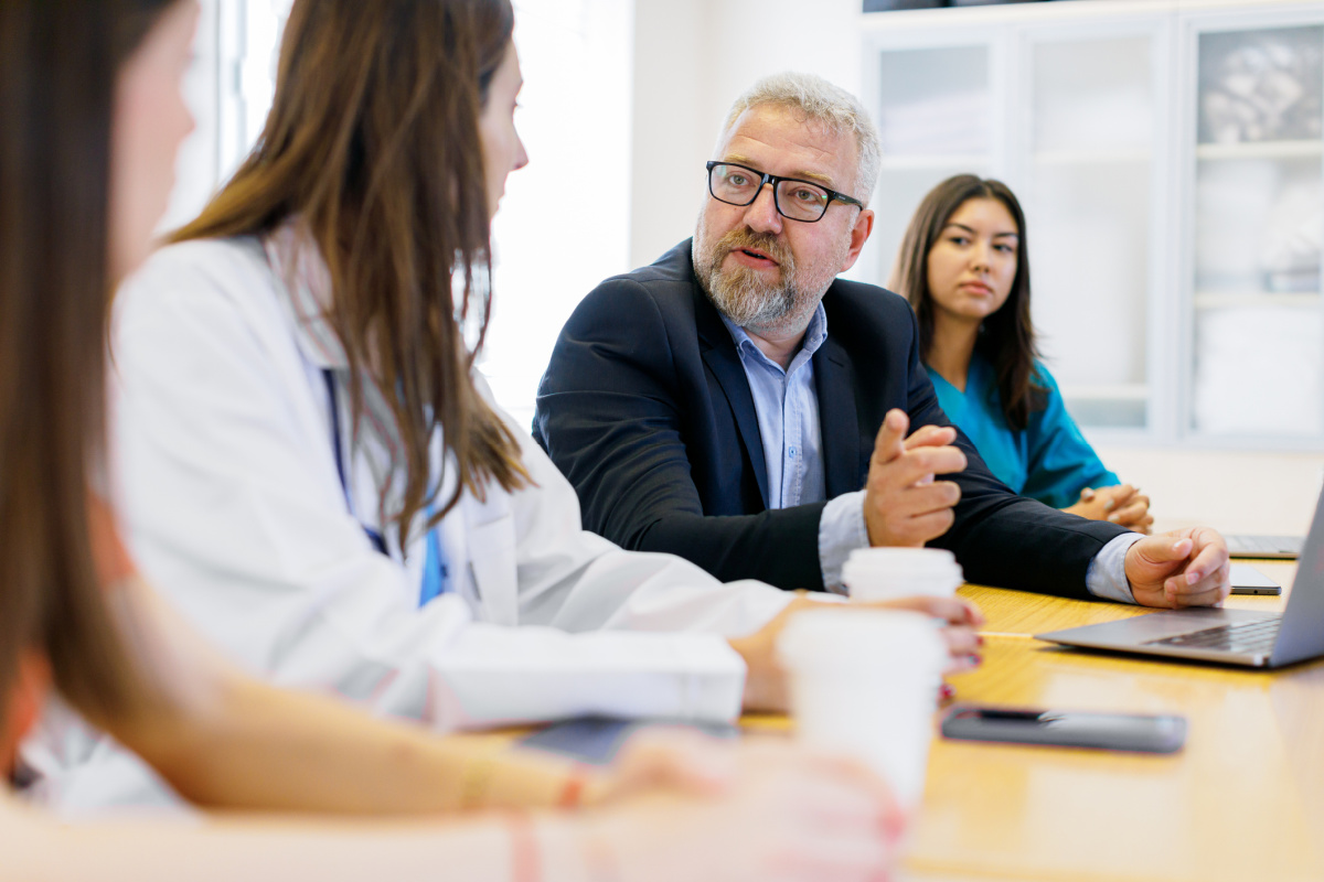 Physician sitting across a conference table in a professional setting